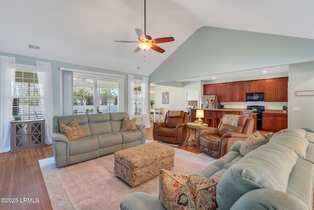 living area with high vaulted ceiling, recessed lighting, a ceiling fan, visible vents, and light wood-style floors