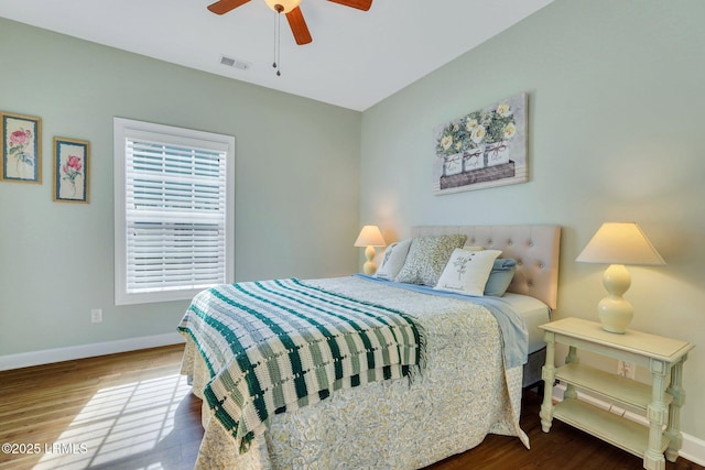 bedroom featuring ceiling fan, wood finished floors, visible vents, and baseboards