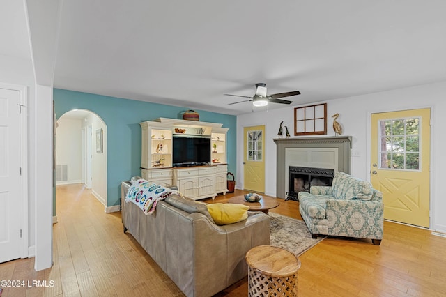 living room featuring ceiling fan, light wood-type flooring, and a fireplace