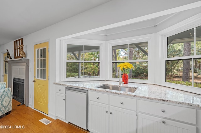 kitchen with white cabinets, sink, dishwashing machine, and light stone counters