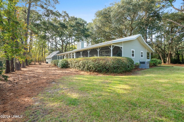 view of side of property featuring a yard, central AC unit, and a sunroom