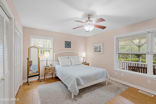 bedroom with multiple closets, ceiling fan, and light wood-type flooring