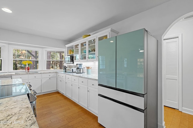 kitchen with white cabinetry, light stone countertops, white fridge, and light hardwood / wood-style flooring