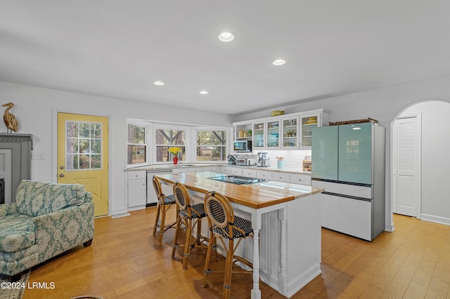 kitchen featuring dishwashing machine, white cabinetry, a kitchen breakfast bar, a kitchen island, and white fridge