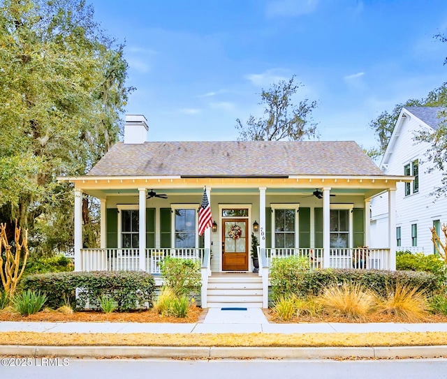 bungalow-style home with covered porch, a chimney, and a ceiling fan