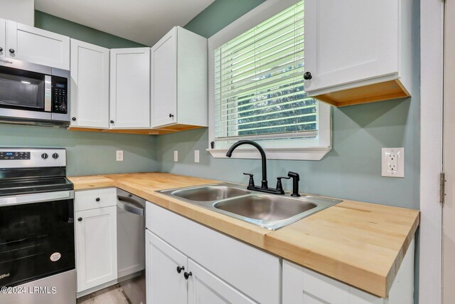 kitchen featuring sink, stainless steel appliances, wooden counters, and white cabinets