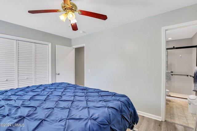 bedroom with connected bathroom, light wood-type flooring, a closet, ceiling fan, and a barn door