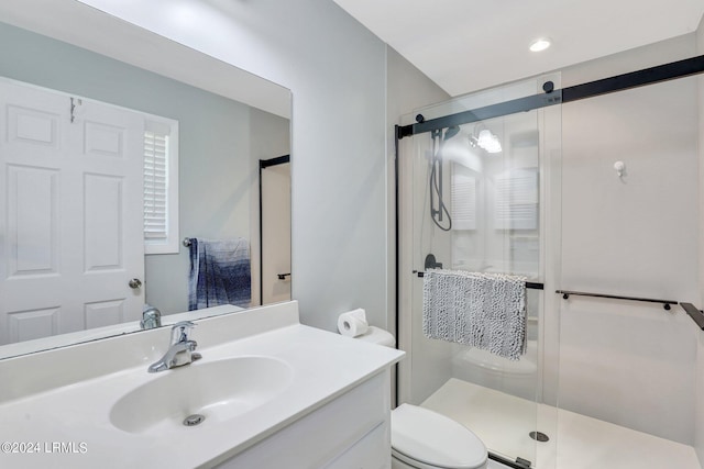 bathroom featuring a shower with door, vanity, and toilet