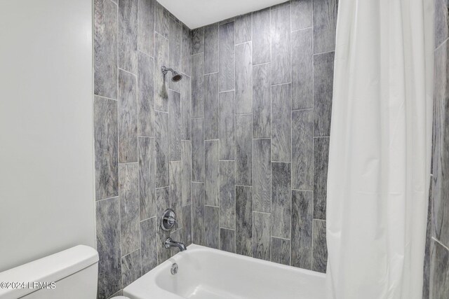 bathroom with shower / bathtub combination with curtain and toilet