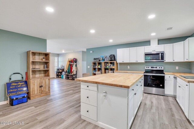 kitchen featuring stainless steel appliances, light hardwood / wood-style floors, butcher block countertops, and white cabinets