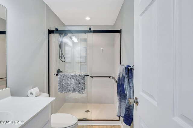 bathroom featuring vanity, toilet, and a shower with shower door