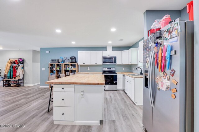 kitchen with white cabinetry, sink, a kitchen bar, a center island, and stainless steel appliances