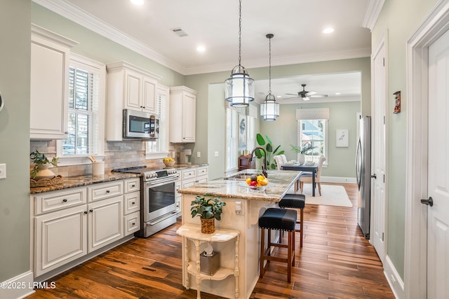 kitchen featuring sink, appliances with stainless steel finishes, a kitchen island with sink, white cabinetry, and light stone counters