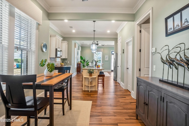 dining area with dark wood-type flooring, ornamental molding, and sink