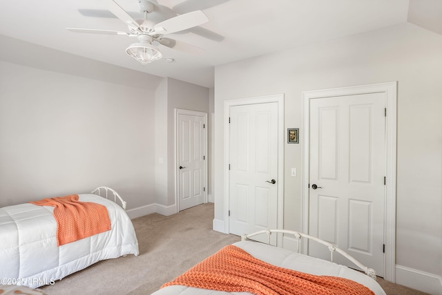 carpeted bedroom with two closets, vaulted ceiling, and ceiling fan