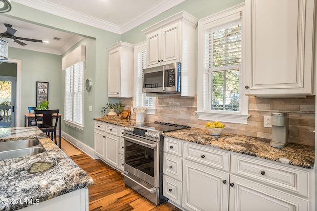 kitchen with appliances with stainless steel finishes, tasteful backsplash, white cabinetry, light hardwood / wood-style floors, and crown molding