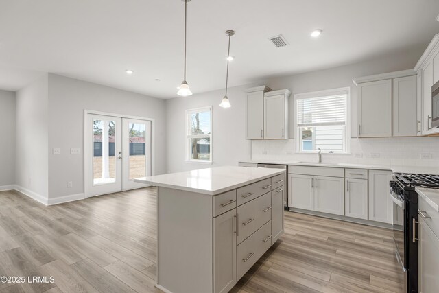 kitchen featuring gas stove, tasteful backsplash, a sink, and visible vents