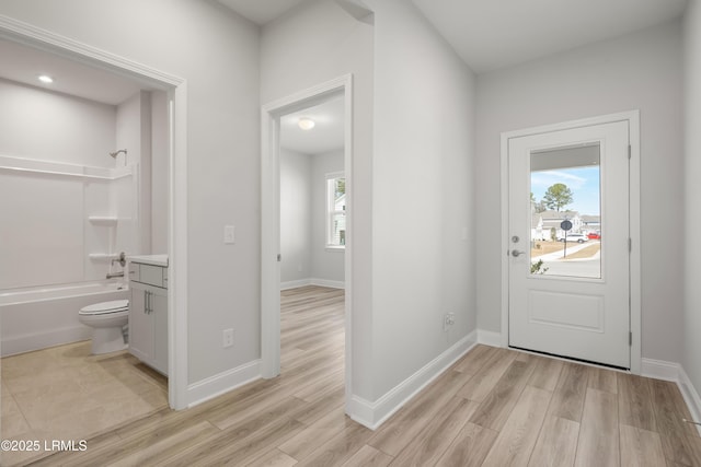 doorway to outside with baseboards, a healthy amount of sunlight, and light wood-style flooring