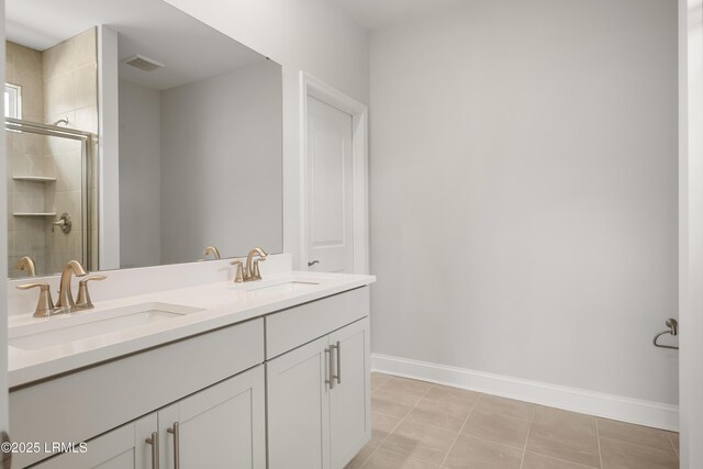 full bath featuring a sink, baseboards, a stall shower, and double vanity