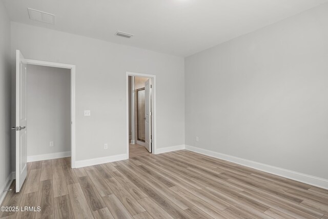 unfurnished bedroom with visible vents, light wood-style flooring, and baseboards