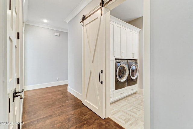 laundry room with wood finished floors, baseboards, separate washer and dryer, crown molding, and a barn door