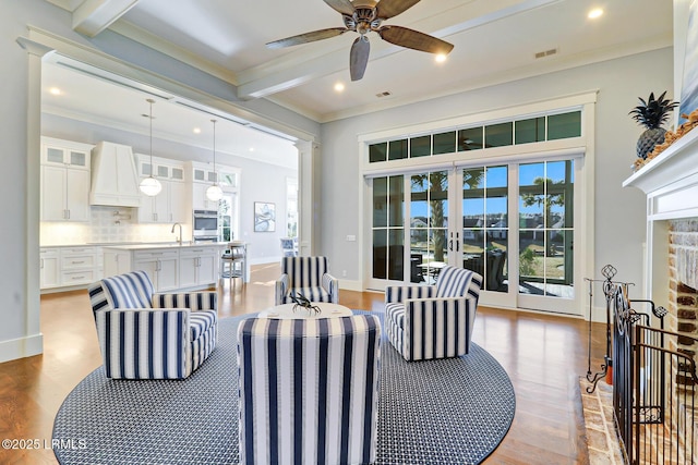 living room featuring visible vents, beam ceiling, a ceiling fan, wood finished floors, and crown molding