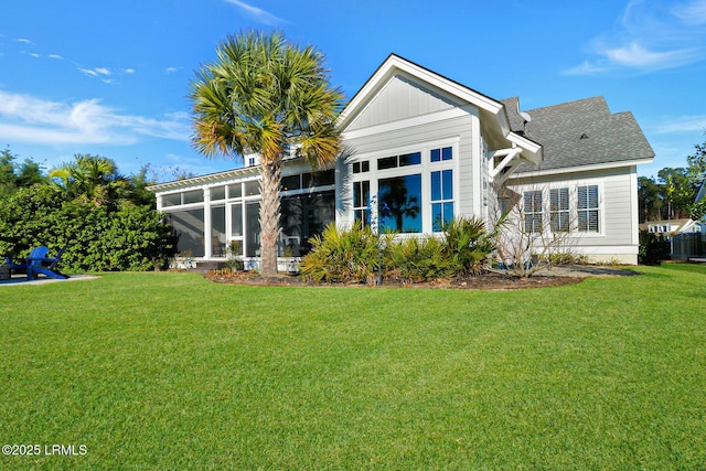 rear view of house with a lawn and a sunroom