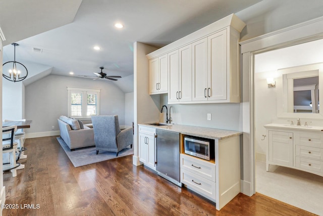 kitchen featuring dark wood-style flooring, a sink, white cabinetry, stainless steel microwave, and ceiling fan with notable chandelier