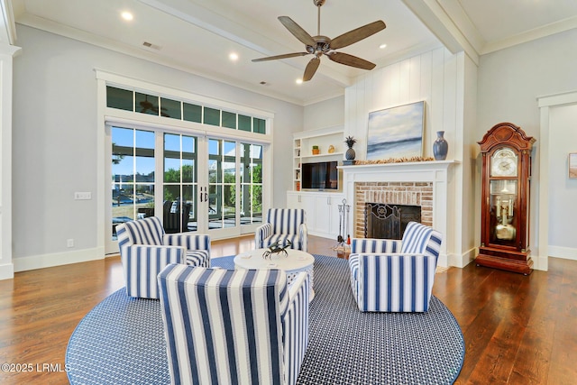 living room with beamed ceiling, a ceiling fan, wood finished floors, and a fireplace