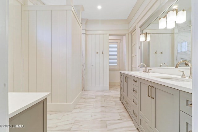 bathroom featuring a sink, baseboards, marble finish floor, and double vanity