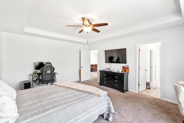 carpeted bedroom featuring connected bathroom, a tray ceiling, ceiling fan, and baseboards