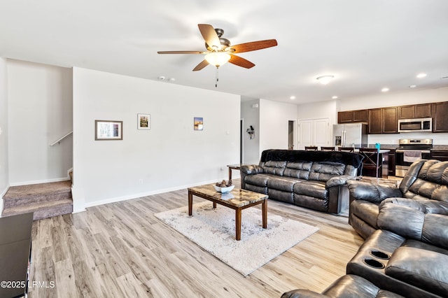 living room with light wood-style flooring, stairway, baseboards, and recessed lighting