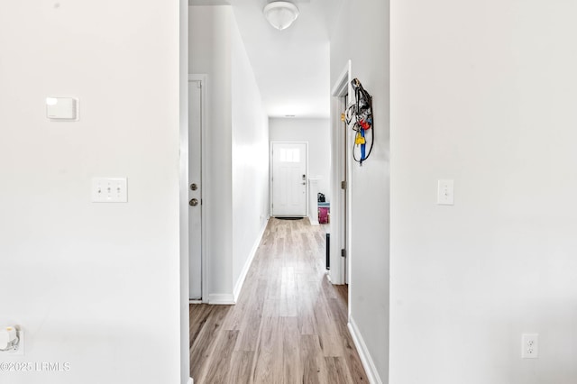 hall featuring light wood finished floors and baseboards