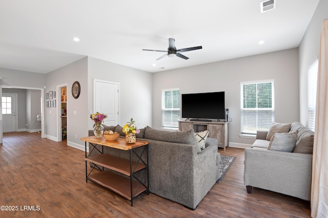 living area featuring dark wood-style floors, a healthy amount of sunlight, visible vents, and baseboards