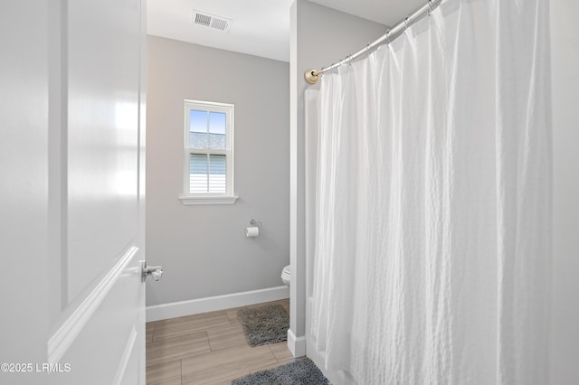 bathroom with toilet, curtained shower, visible vents, and baseboards