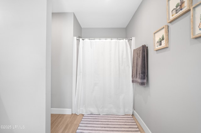 full bath featuring baseboards, a shower with shower curtain, and wood finished floors