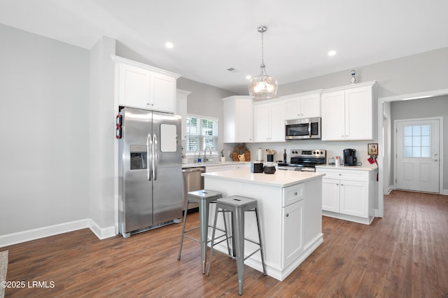 kitchen featuring dark wood-style floors, light countertops, appliances with stainless steel finishes, white cabinets, and a kitchen island