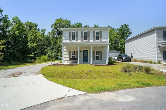 view of front of house featuring covered porch, driveway, a front yard, and an outbuilding