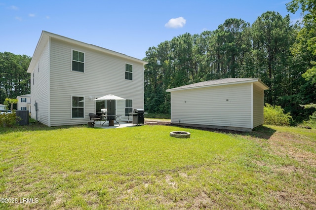 back of property with a lawn, central AC unit, an outdoor fire pit, a patio area, and an outdoor structure