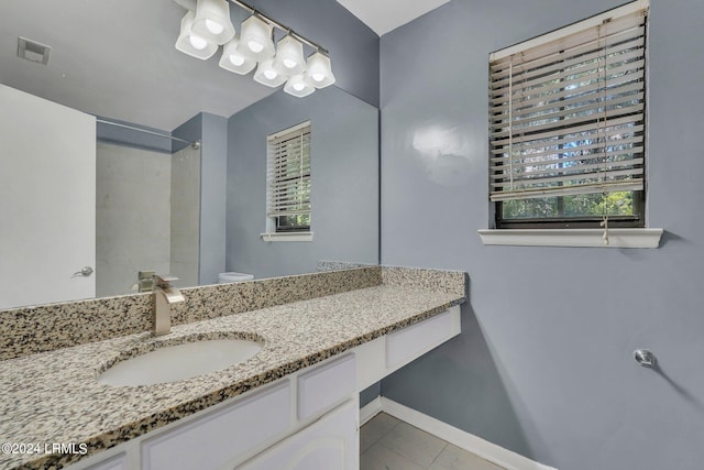 bathroom featuring tile patterned floors, vanity, toilet, and a shower