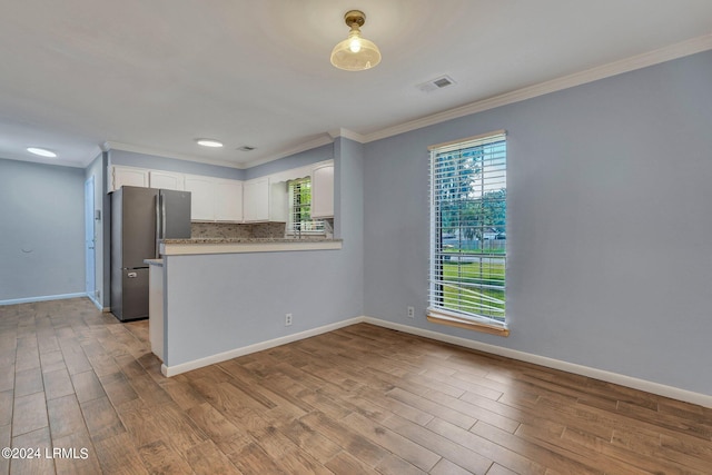 kitchen with tasteful backsplash, stainless steel fridge, crown molding, and white cabinets