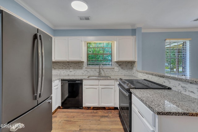 kitchen with range with electric cooktop, black dishwasher, sink, white cabinets, and stainless steel fridge