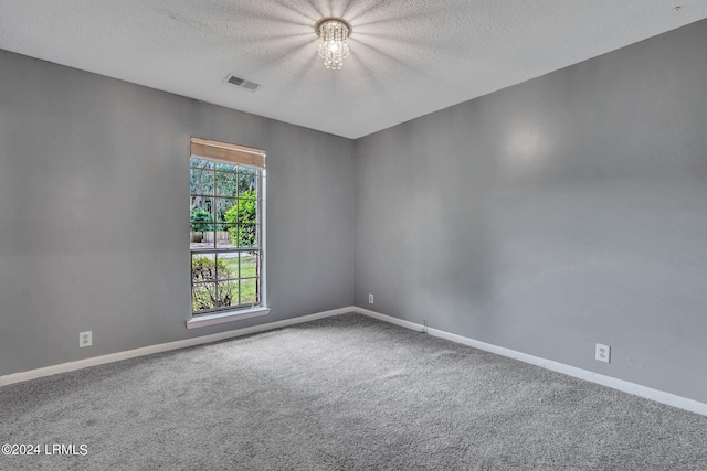 carpeted empty room with a textured ceiling