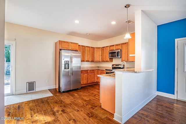 kitchen featuring appliances with stainless steel finishes, dark wood-type flooring, pendant lighting, and kitchen peninsula