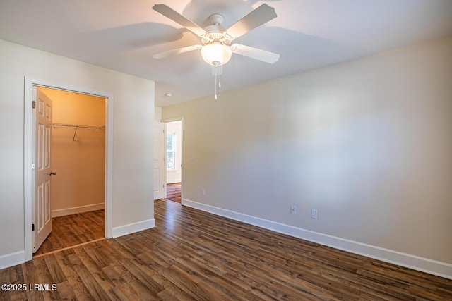 unfurnished bedroom featuring ceiling fan, a spacious closet, dark hardwood / wood-style flooring, and a closet