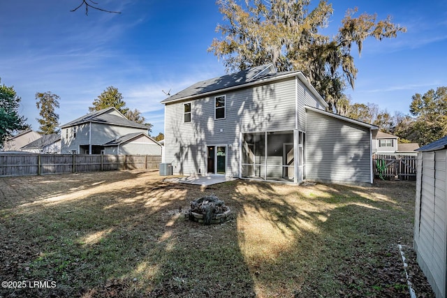 rear view of property featuring a yard, cooling unit, and an outdoor fire pit