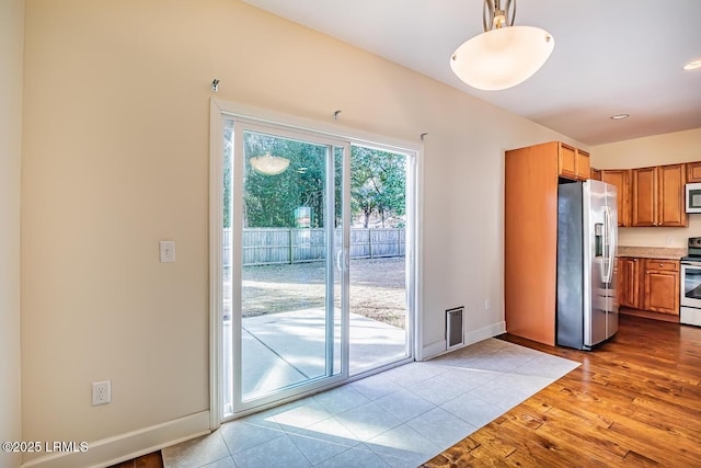 kitchen featuring hanging light fixtures, light hardwood / wood-style flooring, and appliances with stainless steel finishes