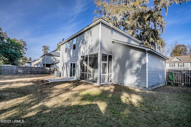 rear view of house with a patio, a sunroom, central air condition unit, and a lawn