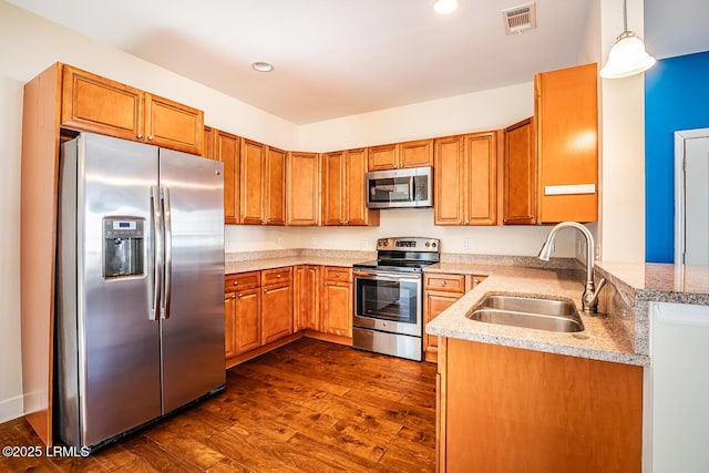 kitchen featuring hanging light fixtures, appliances with stainless steel finishes, sink, and dark hardwood / wood-style flooring