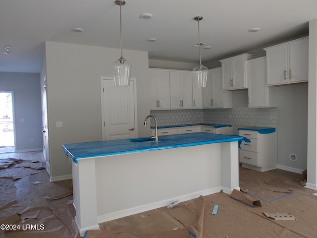 kitchen with a kitchen island with sink, sink, hanging light fixtures, and white cabinets